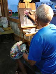 Steve Weidert painting Monday night at the Mooreland Free Fair.